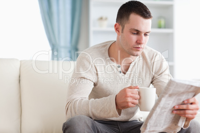 Calm man having a tea while reading the news