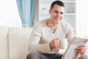 Happy man having a tea while reading the news