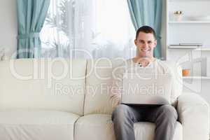 Man using a laptop while sitting on a sofa