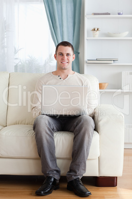 Portrait of a man using a laptop while sitting on a sofa