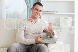 Happy man shopping online with the thumb up