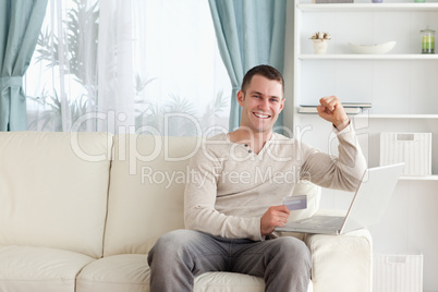 Happy man shopping online with the fist up