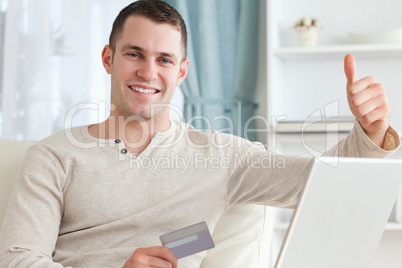 Smiling man shopping online with the thumb up