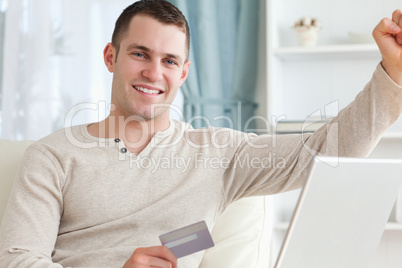 Smiling man shopping online with the fist up