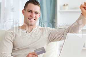 Smiling man shopping online with the fist up