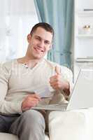 Portrait of a man shopping online with the thumb up