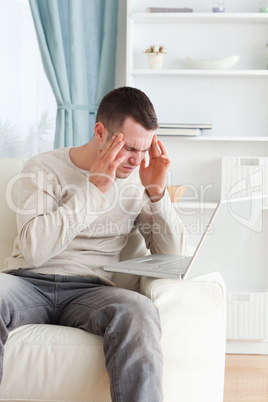 Portrait of a man having a headache while using a laptop