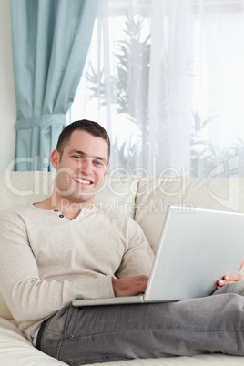 Portrait of a smiling man relaxing with a laptop