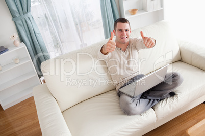 Man relaxing with a notebook with the thumbs up
