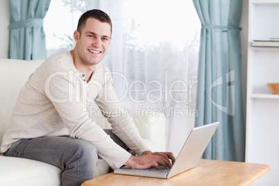 Smiling man typing on his laptop