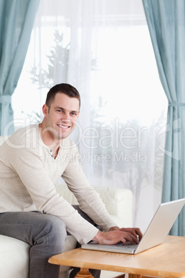 Portrait of a smiling man typing on his laptop