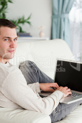 Portrait of a man lying on his couch with a laptop