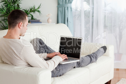 Man lying on his couch using a laptop