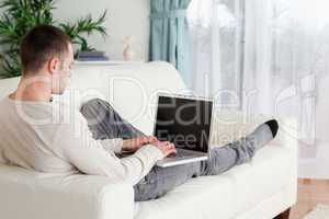 Man lying on his couch using a laptop