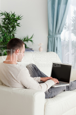 Portrait of a man lying on his couch using notebook