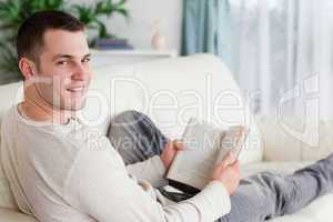 Portrait of a man lying on his couch holding a book