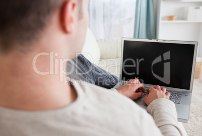 Man lying on his couch while using a laptop