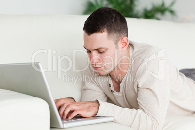 Man lying on a sofa using a laptop