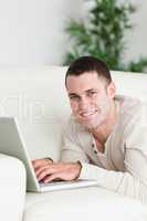 Portrait of a man lying on a sofa with a laptop