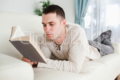 Man lying on a couch to read a book