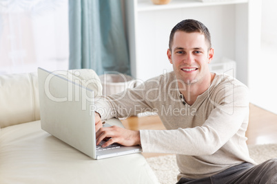 Smiling man sitting on a carpet posing with a notebook