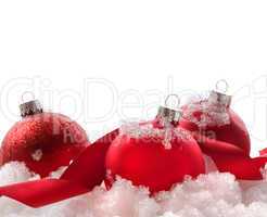 Red christmas balls and ribbon in snow on white