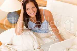 Beautiful woman working on computer in bed