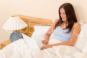 Beautiful woman working on computer in bed