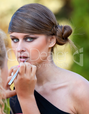 Makeup master applying lipstick with brush