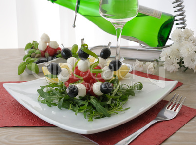 Appetizer of mozzarella, cherry tomatoes and olives with Arugula