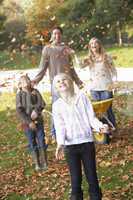 Family throwing autumn leaves into the air in garden