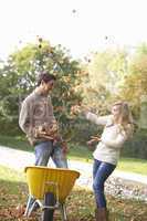 Young couple having fun with autumn leaves in garden