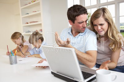 Young couple thinking and looking at a laptop computer