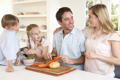Happy family peeling vegetables in kitchen