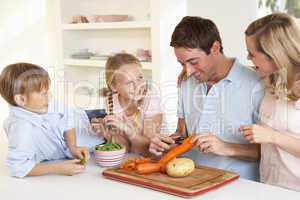 Happy family peeling vegetables in kitchen