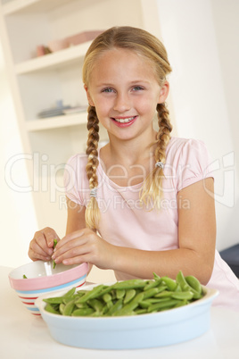 Happy girl splitting peas in kitchen