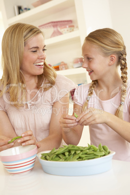 Young woman with child splitting pea in kitchen