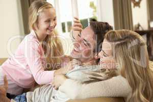 Happy young family playing together on sofa