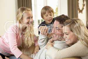 Happy young family playing together on sofa