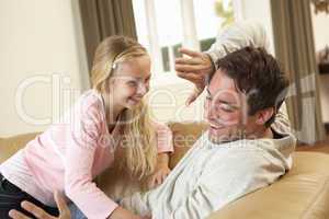 Young father with girl having fun on sofa