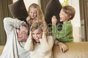 Happy young family having fun with pillows on sofa