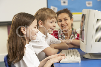 Schoolchildren In IT Class Using Computer with teacher