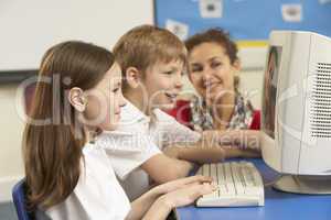 Schoolchildren In IT Class Using Computer with teacher