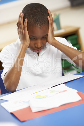 Stressed Schoolboy Studying In Classroom