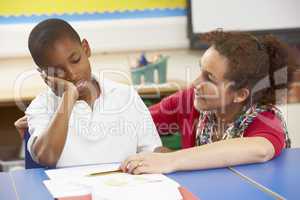 Unhappy Schoolboy Studying In Classroom With Teacher