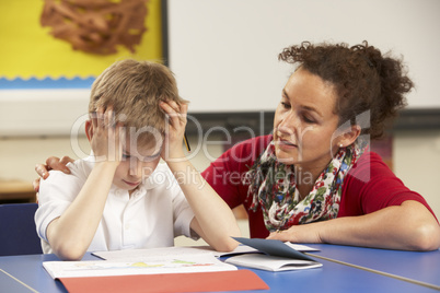 Stressed Schoolboy Studying In Classroom With Teacher