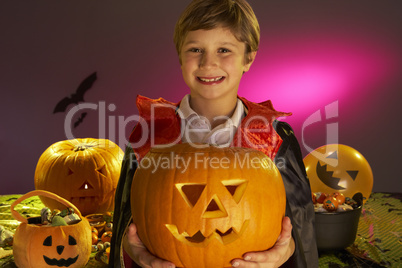 Halloween party with a boy child holding carved pumpkin