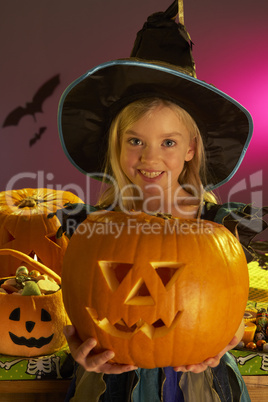 Halloween party with a child holding carved pumpkin