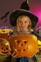 Halloween party with a child holding carved pumpkin