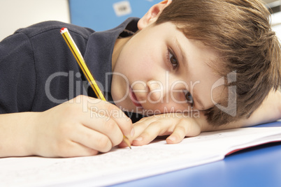 Unhappy Schoolboy Studying In Classroom